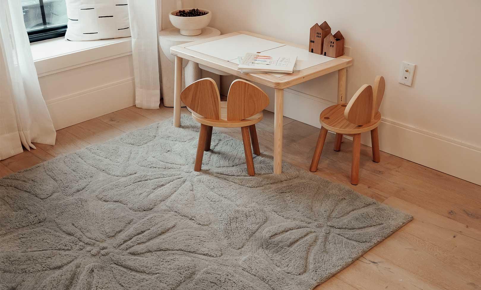 Washable wool children's rug with a colorful floral field design, featuring vibrant flowers in soft pastel tones.