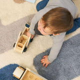 Toddler playing on a stacked wool area rug, showcasing its soft texture and machine-washable design for child-friendly spaces.