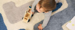 Toddler playing on a stacked wool area rug, showcasing its soft texture and machine-washable design for child-friendly spaces.