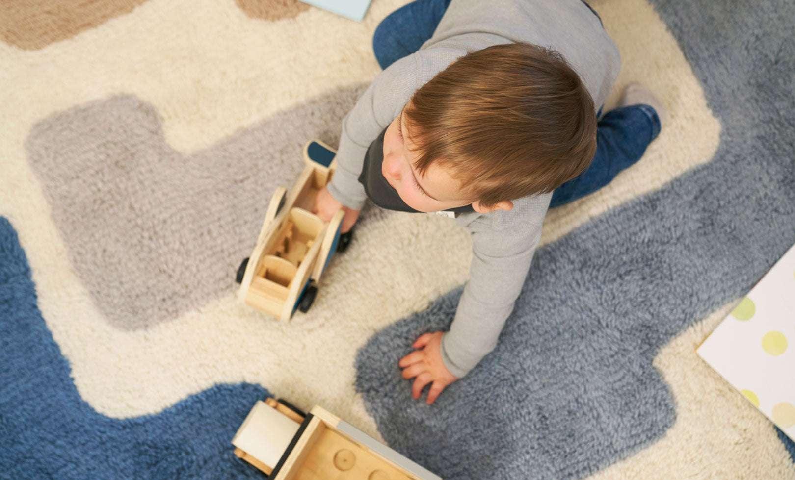 Toddler playing on a stacked wool area rug, showcasing its soft texture and machine-washable design for child-friendly spaces.