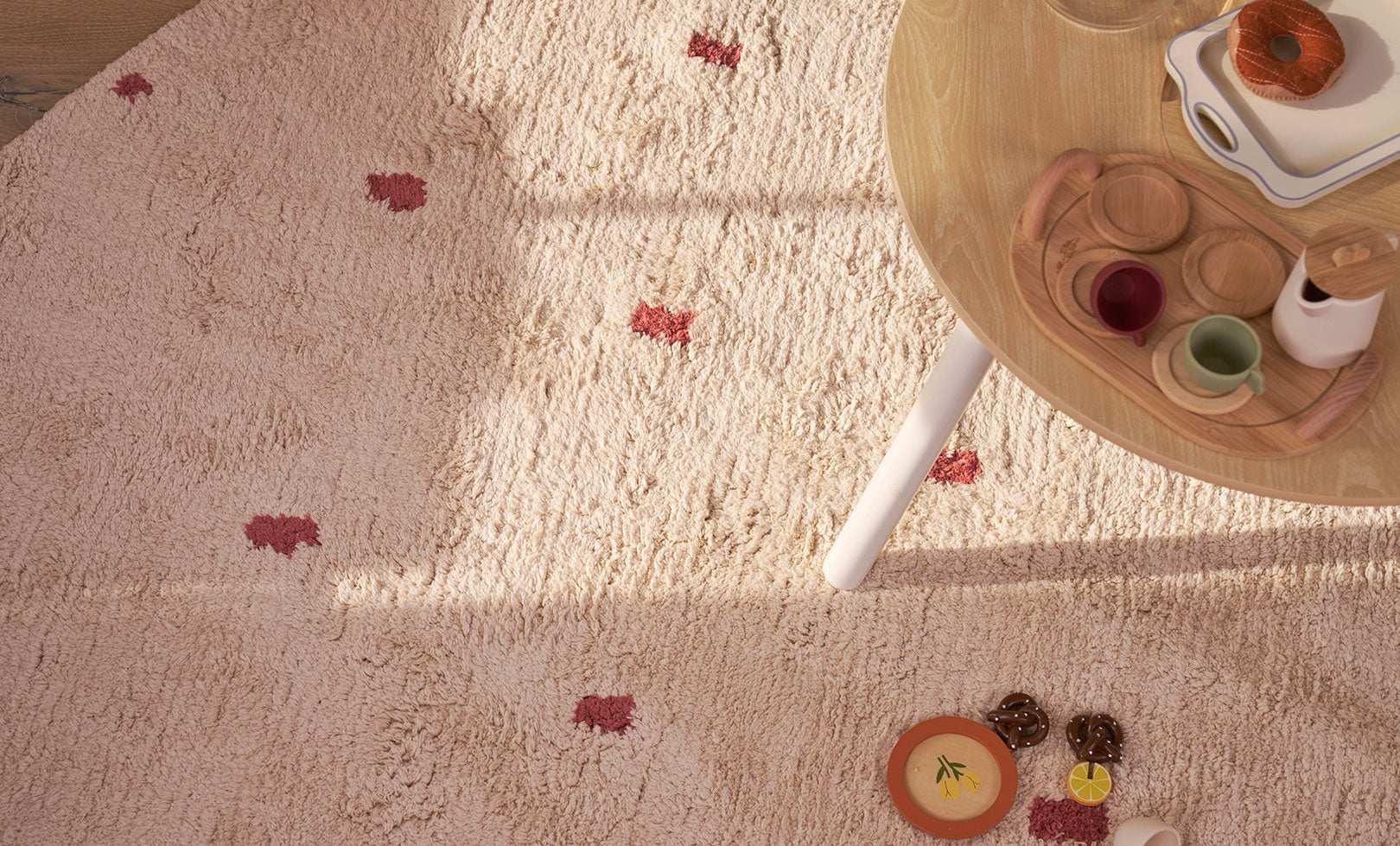 Warm rust-colored dotted rug made from certified organic cotton, a cozy and washable addition to play-friendly spaces.