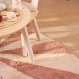 Vibrant pink pinwheel rug with whimsical symmetry, crafted in washable wool for joyful and practical nursery design.
