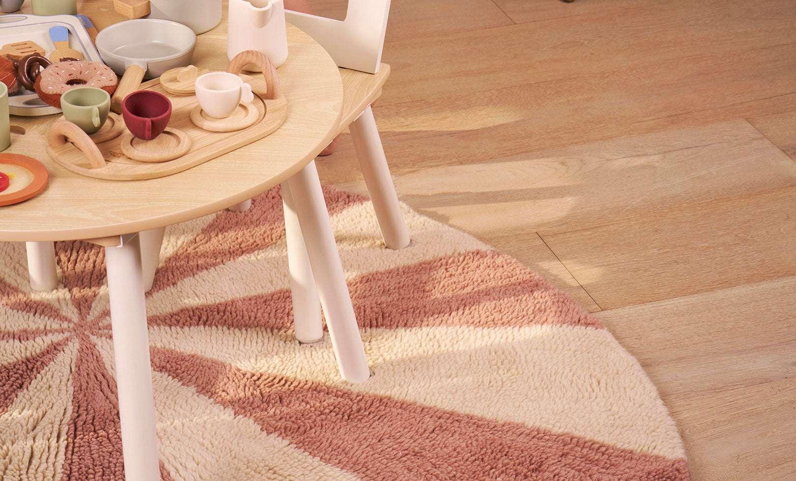 Vibrant pink pinwheel rug with whimsical symmetry, crafted in washable wool for joyful and practical nursery design.
